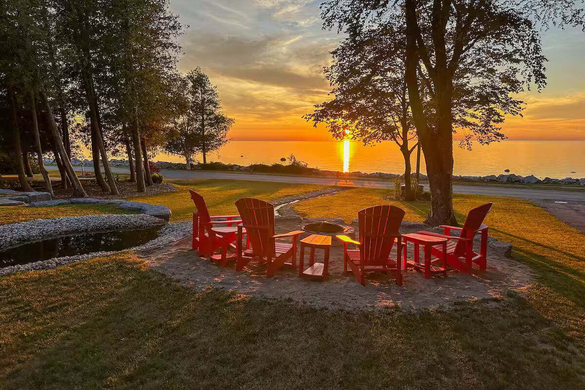 Une vue sur le coucher de soleil, avec une table et des chaises disposées sur une pelouse, près d’une étendue d’eau.