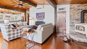 A cozy living room with a fireplace, a checkered sofa, and a stone wall. - Lake Huron Shore Retreat (Kincardine)