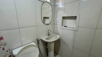 A bathroom with a toilet, sink, and mirror.
