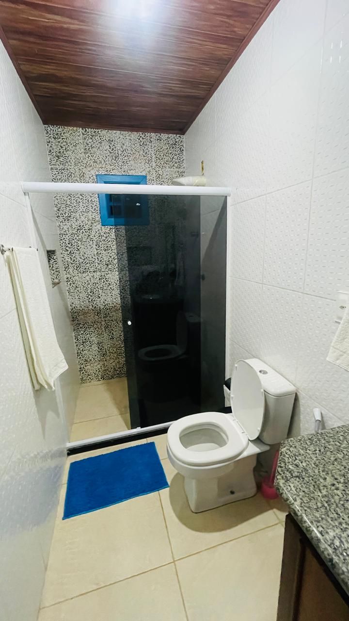 A small bathroom with a white toilet, a blue mat, and a shower area.