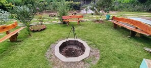A garden with a fire pit, wooden benches, and a pathway. - Vale das Rainhas Pousada Santo Amaro BA (Santo Amaro)