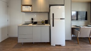 Eine moderne Küche mit Einbau-Mikrowelle, Kühlschrank und einem Essbereich mit Fernseher.