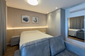 A modern bedroom with a bed, bedside tables, a sofa, and two framed leaf artworks on the wall. - Glass Art 96 (São Paulo)