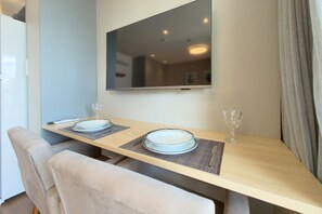 A dining area with a table set for two, a mirror above, and a view of the room. - Glass Art 96 (São Paulo)