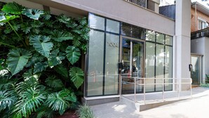 Un edificio moderno con amplios ventanales, el número '1004' en la fachada y una barandilla metálica al frente.