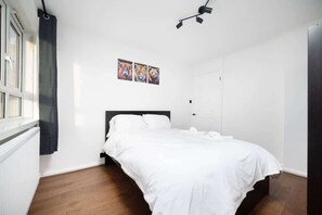 A bedroom with a bed, a window, and a door. - Spacious 3 Bed Kensington Flat | BeeMyGuest® (London)
