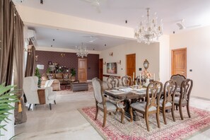 Un salon spacieux avec une cheminée, un coin repas avec une grande table et des chaises en bois, et un lustre.