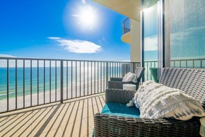 A balcony with wicker furniture, a view of the ocean, and a clear sky. - Phoenix West 1008 3 Bedroom Condo (Orange Beach)