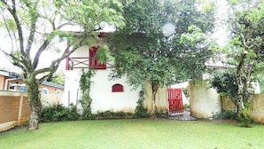 Um edifício branco com detalhes vermelhos, cercado por um gramado e árvores.