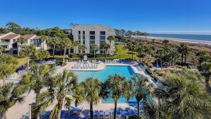 Ein Resort mit großem Pool, Liegestühlen und Blick auf den Strand.