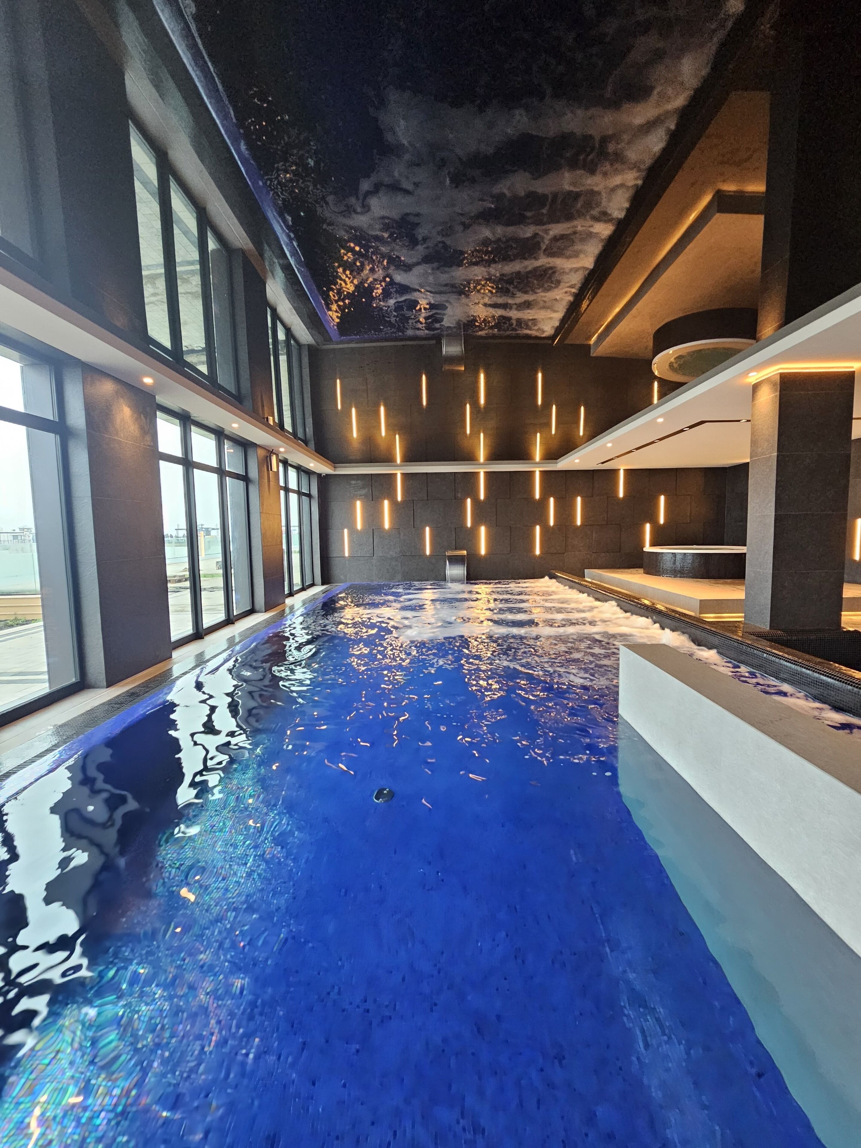 Een binnenzwembad, ligstoelen bij het zwembad