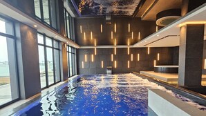 An indoor swimming pool with a clear view of the sky through large windows, a modern ceiling design, and a sleek, minimalist poolside area. - Baltic Infinity (Międzyzdroje)