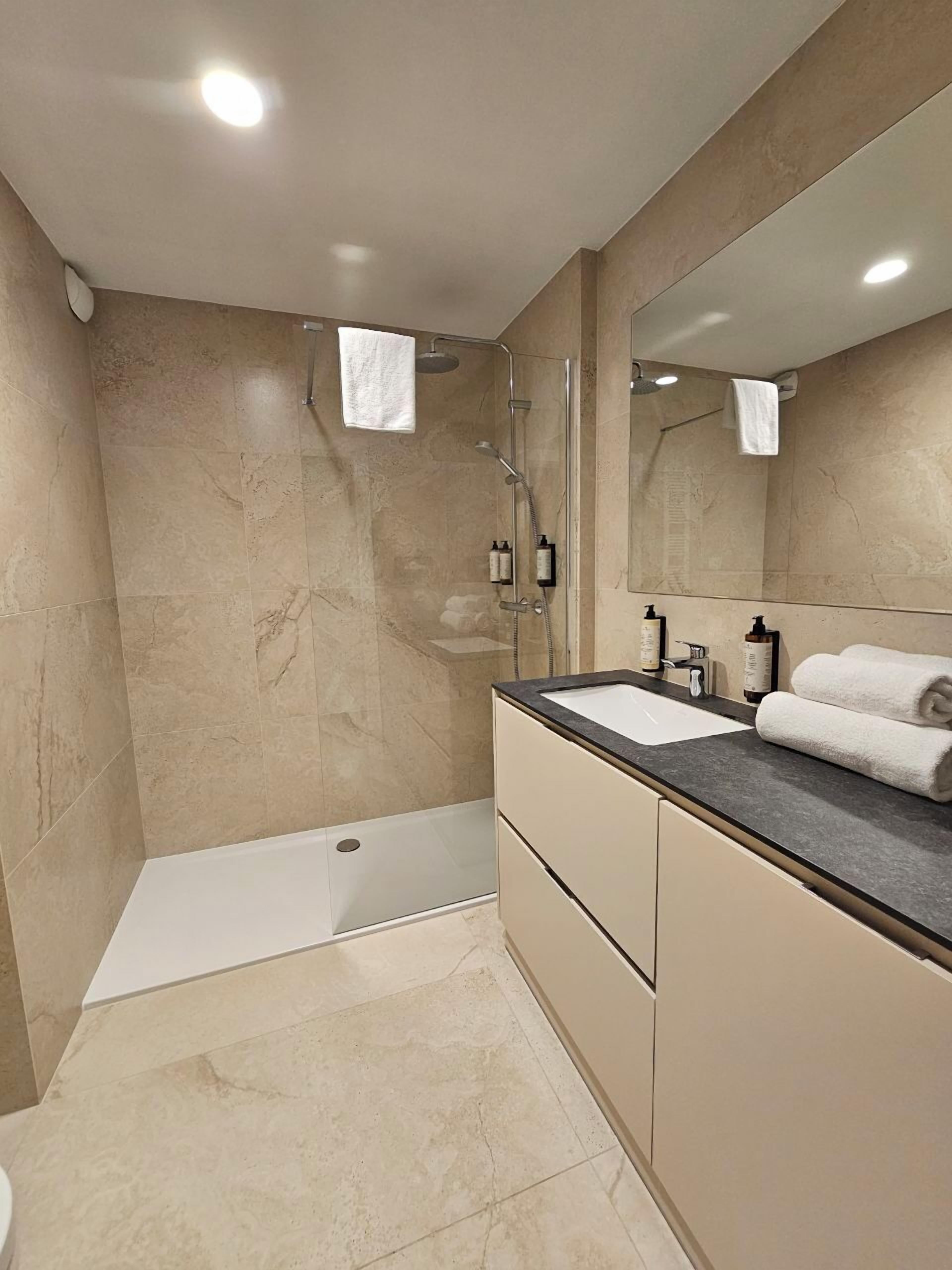 Un bagno moderno con doccia, lavandino e specchio.