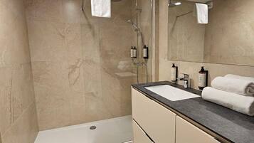 Un bagno moderno con doccia, lavandino e specchio.