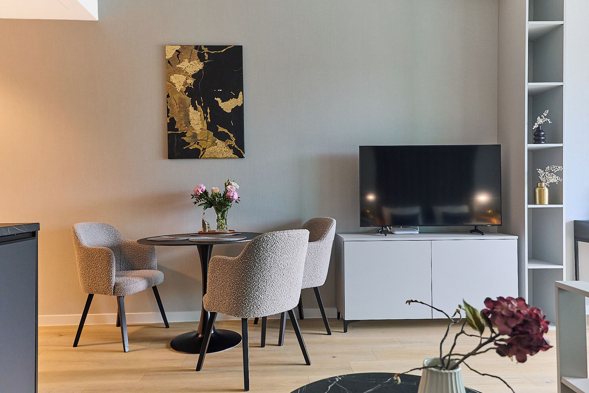 Uma sala de estar moderna com televisão, mesa de centro e quatro cadeiras.