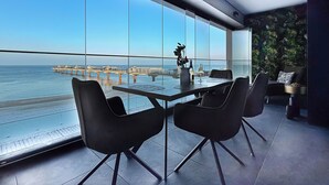 A modern dining area with a panoramic sea view, featuring a table with chairs and a decorative vase. - Baltic Infinity (Międzyzdroje)