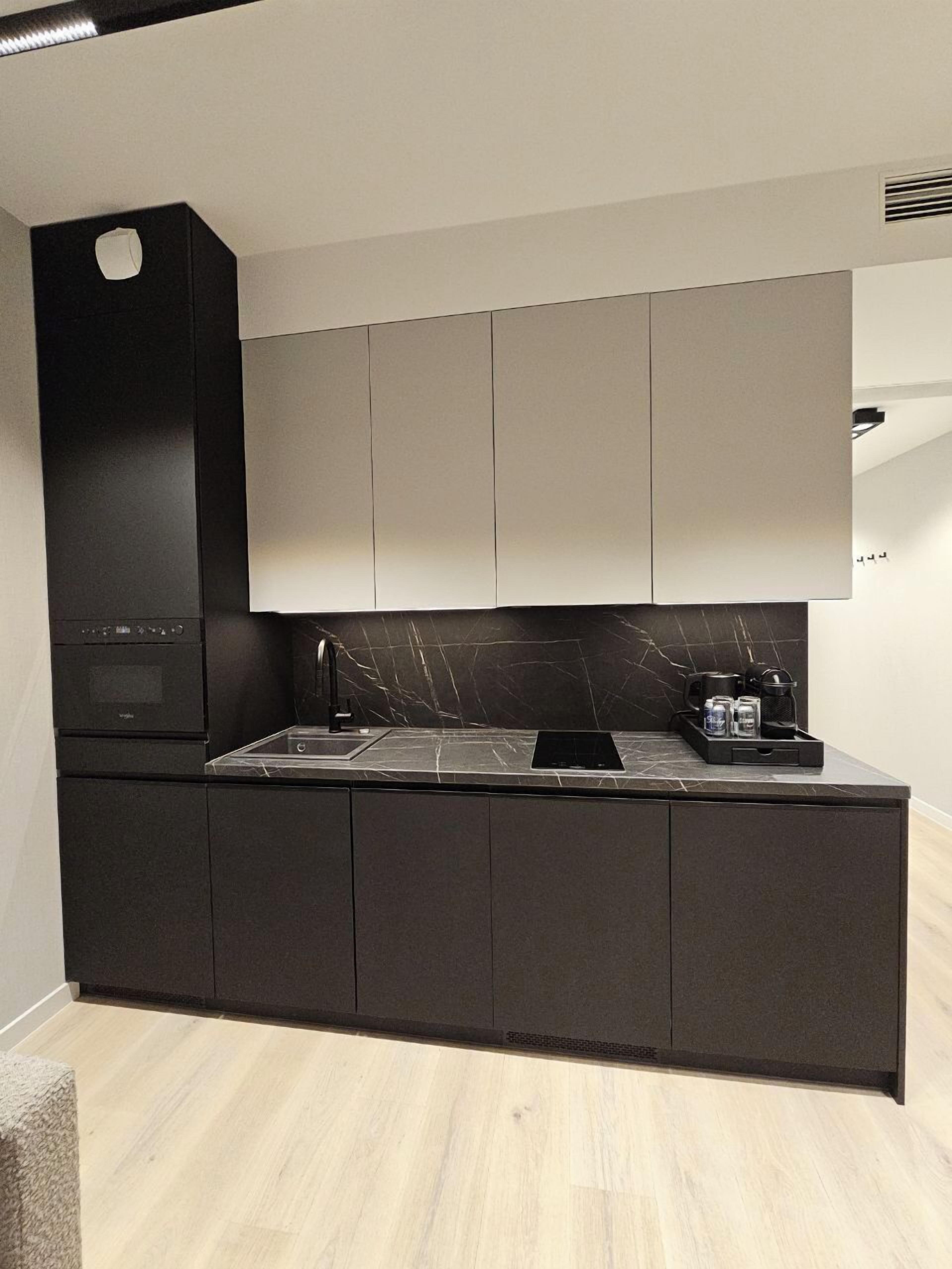 A modern kitchen with a built-in oven, a black range hood, and a marble countertop.