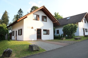 Une maison à deux étages, dotée d’un toit en pente, d’une porte d’entrée et d’un petit porche.