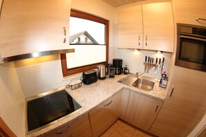 Una cocina moderna con estufa integrada, cafetera, tostadora y pileta.