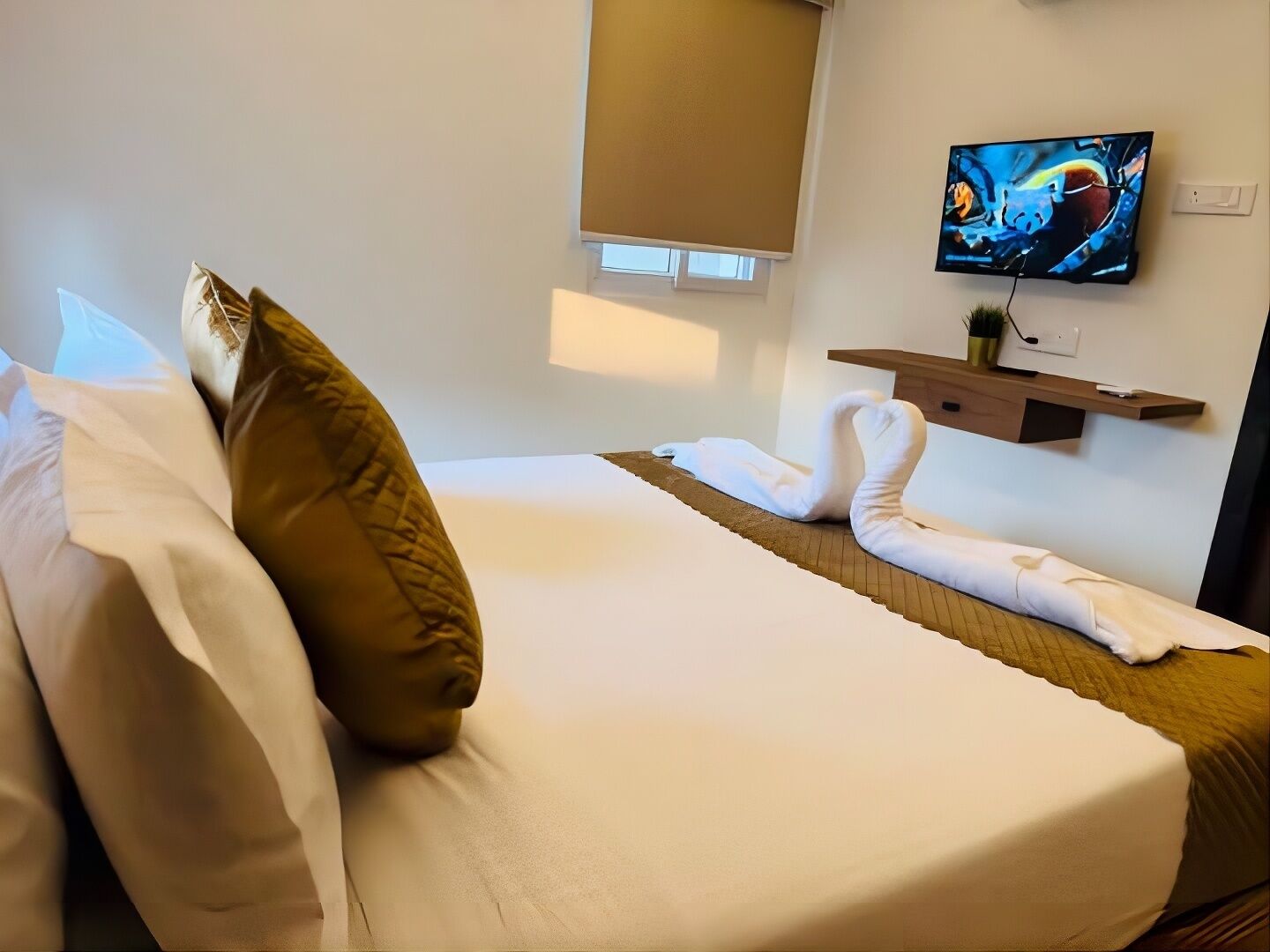 Une chambre d’hôtel avec un lit, des oreillers, une télévision et un porte-serviettes.