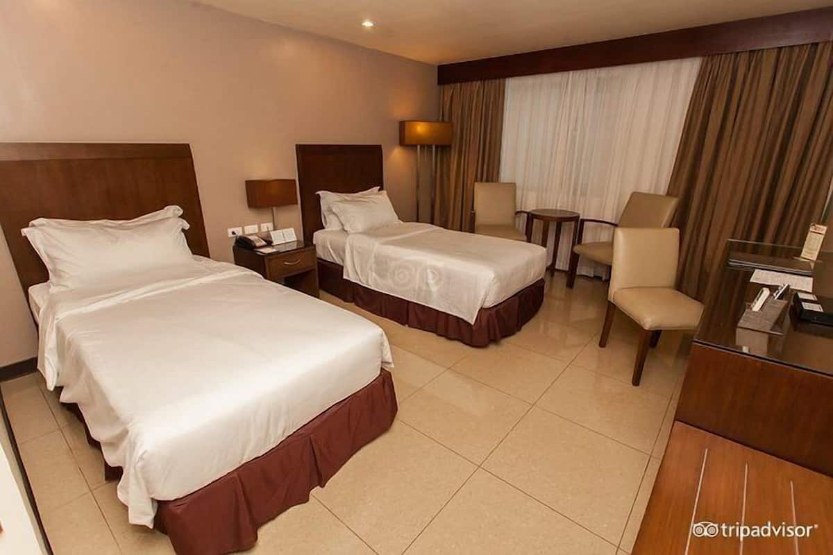 Una habitación de hotel con dos camas, un escritorio, una silla y una mesita.