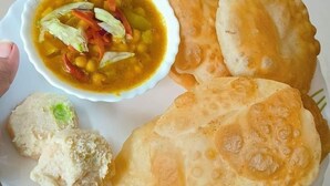 Ein Teller mit zwei Sorten frittiertem Brot, eine Schüssel Suppe mit Gemüse und ein kleines Stück Brot.