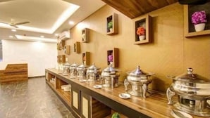Ein Buffet mit mehreren Servierstationen, einer Holztischplatte und Wandblumenarrangements.