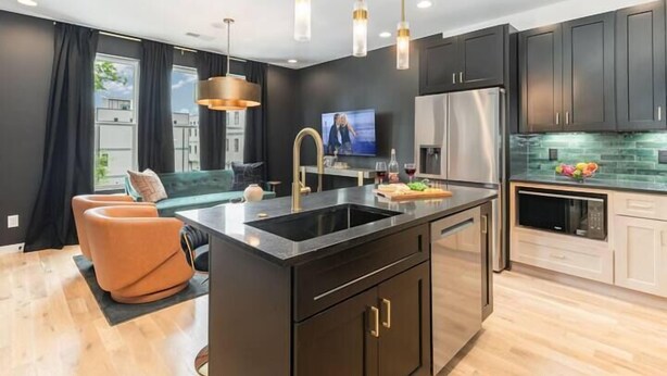 A modern kitchen with dark cabinetry, a central island, stainless steel appliances, and pendant lighting. - Harmony Heights Duo w/ Hot Tub & Skyline Views (Nashville)