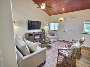 A living room with a flat-screen TV, a fireplace, a ceiling fan, and wicker chairs. - Sky Blue 2Bdrm Guest House | Country Escape | Minutes to Beaches & Wineries (Arroyo Grande)
