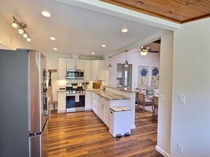 A modern kitchen with white cabinetry, stainless steel appliances, and a wooden floor. - Sky Blue 2Bdrm Guest House | Country Escape | Minutes to Beaches & Wineries (Arroyo Grande)