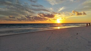 A beach with a sunset, waves, and a few people walking. - Calm Sands# 1002 New Property Chateau La Mer II 2-Bd 2-Bath Ground Floor (Destin)
