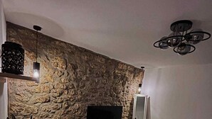 Ein modernes Wohnzimmer mit Steinwand, Flachbildfernseher, grauem Sofa und Couchtisch.