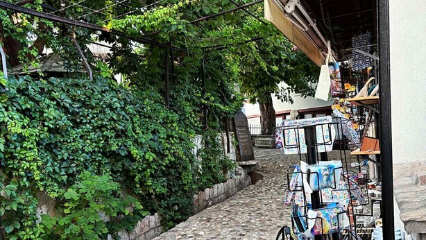Eine enge Kopfsteinpflasterstraße mit einem kleinen Laden, der Postkarten und andere Artikel verkauft.