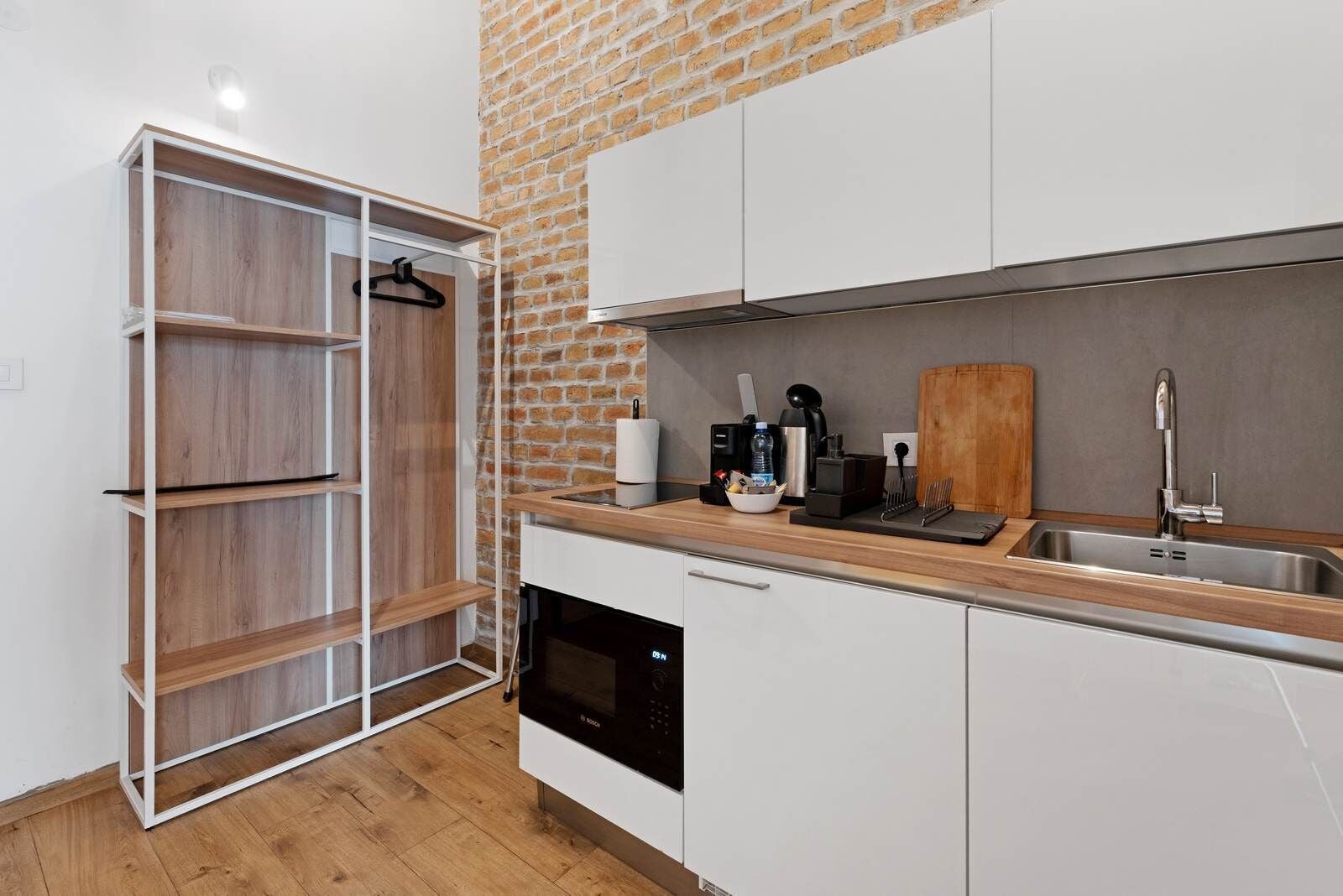 Una cocina moderna con armarios blancos, una encimera de madera, una pared de ladrillo y un lavavajillas.