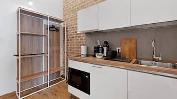 Una cocina moderna con armarios blancos, una encimera de madera, una pared de ladrillo y un lavavajillas.