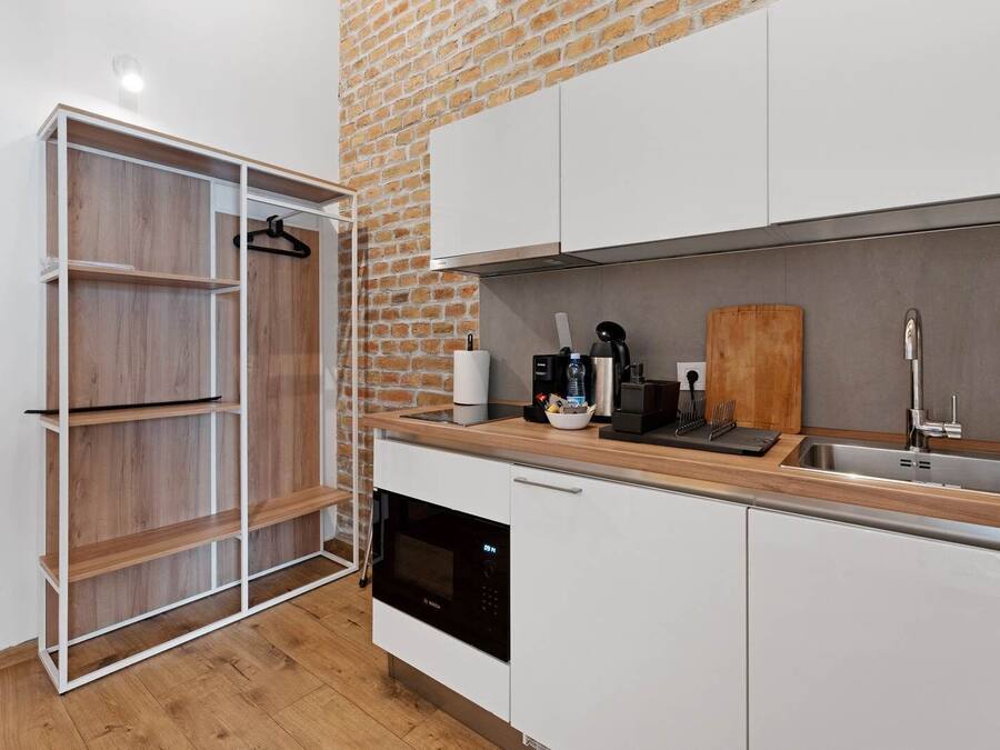 Una cocina moderna con armarios blancos, una encimera de madera, una pared de ladrillo y un lavavajillas.