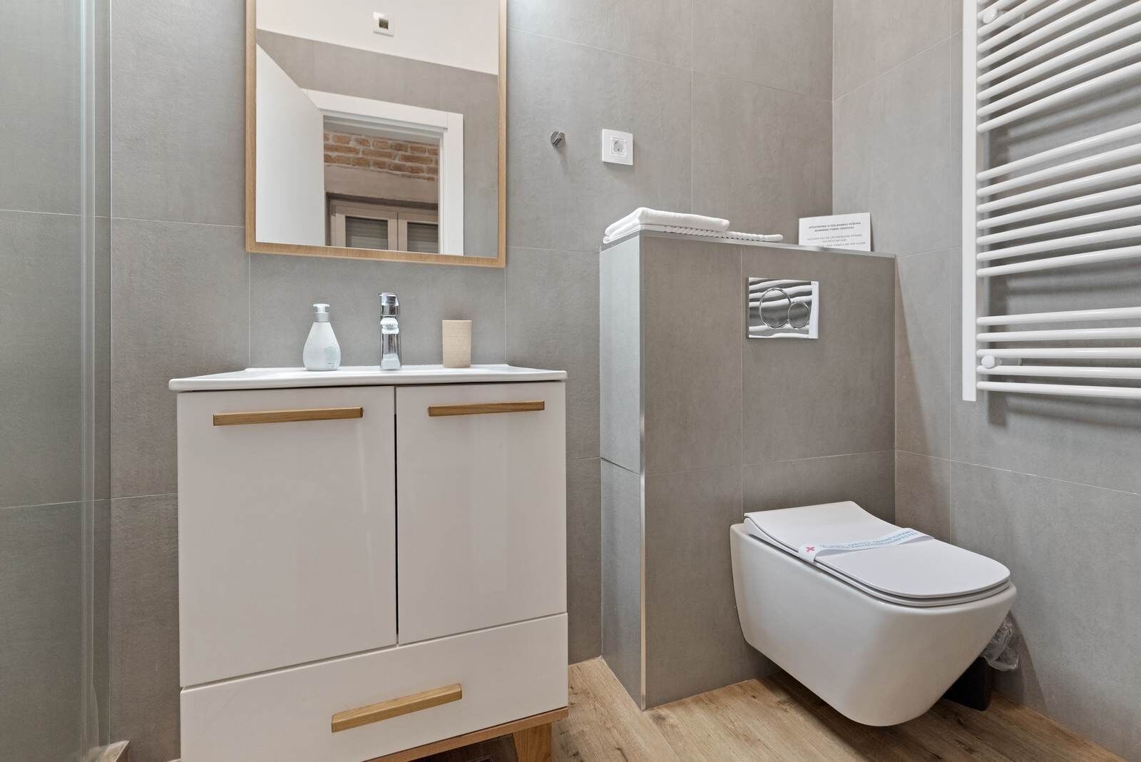 A bathroom with a toilet, a sink with a mirror, and a towel rack.