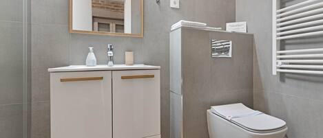 A bathroom with a toilet, a sink with a mirror, and a towel rack.