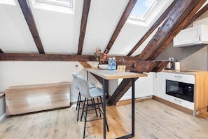A modern kitchen with wooden beams, a dining area with chairs, and a skylight.