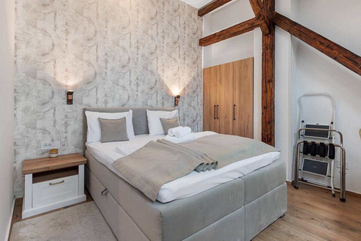 Un dormitorio con cama, mesitas de noche, armario y silla de ruedas.