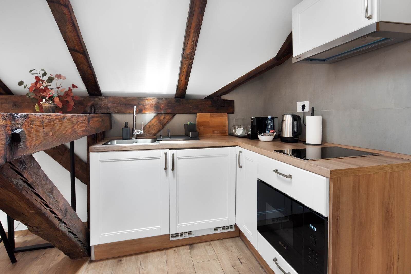 A kitchen with white cabinets, a wooden countertop, a Bosch dishwasher, and a coffee maker.