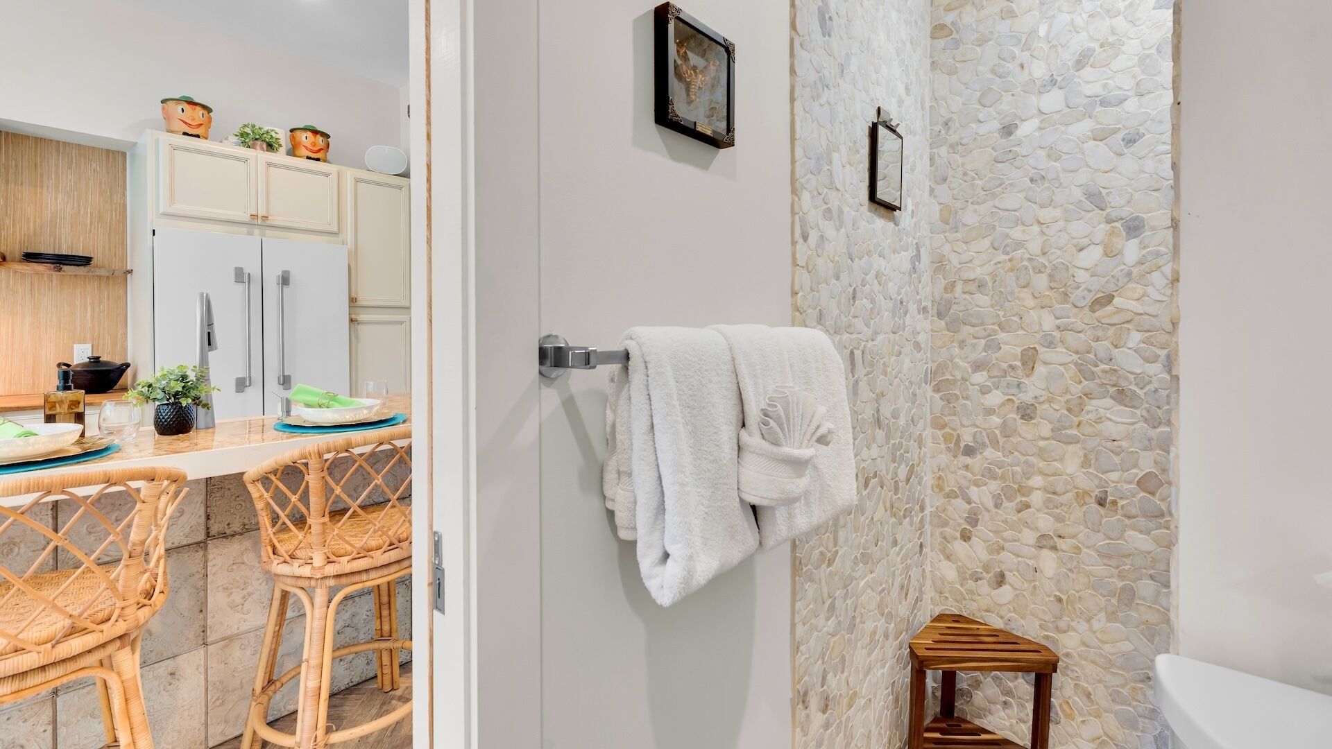 Een moderne badkamer met een stenen muur, een klein houten krukje en een witte handdoek aan een rek.