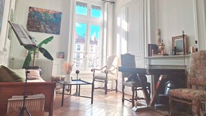 A well-lit room with a large window, a piano, a table, and several chairs. - Breathtaking view in the heart of Lyon (Lyon)