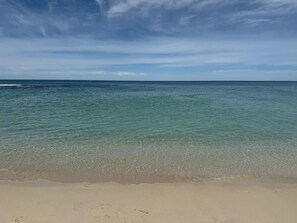 Une plage avec une eau claire et peu profonde et un rivage sablonneux.