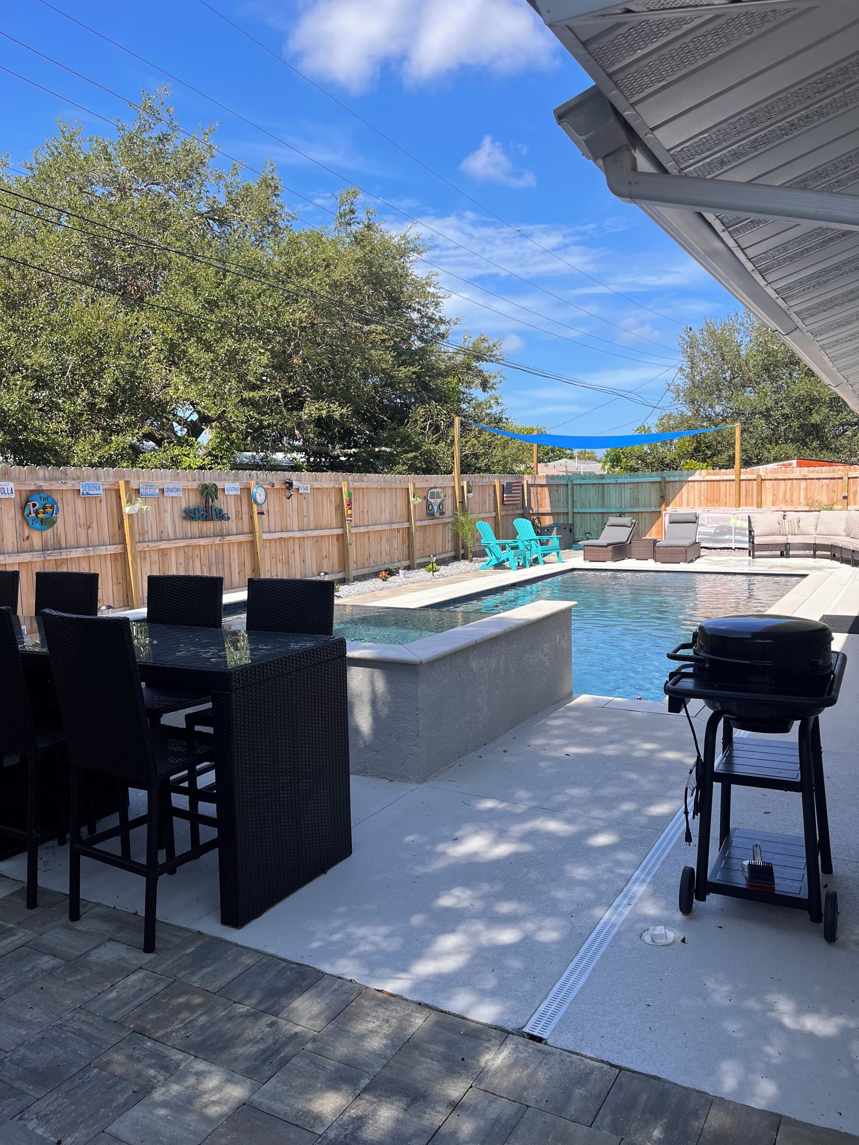 An outdoor patio with a pool, a grill, and a wooden fence with decorative elements.