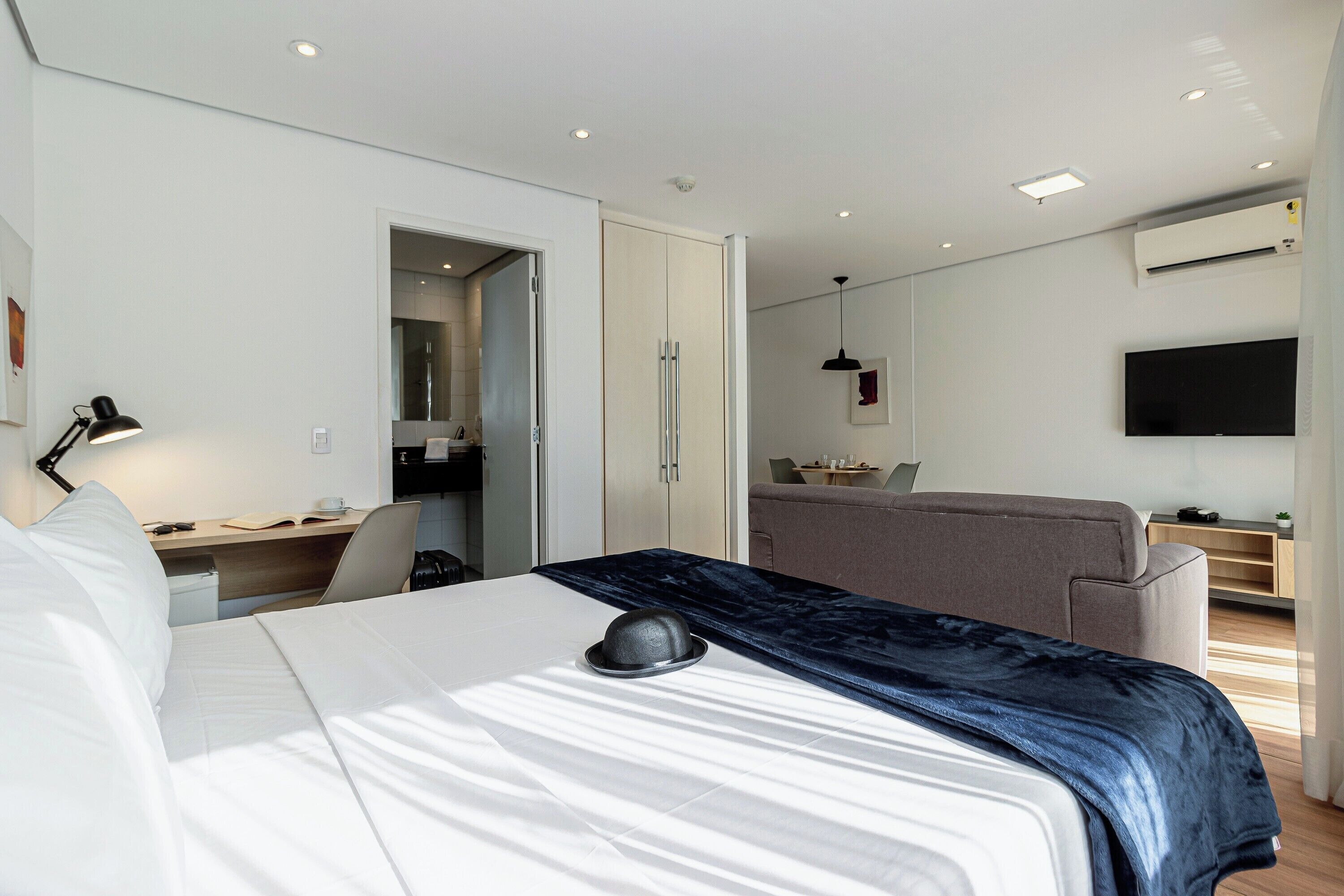 A modern hotel room with a bed, desk, chair, and a television.