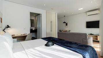 A modern hotel room with a bed, desk, chair, and a television.
