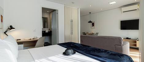 A modern hotel room with a bed, desk, chair, and a television.