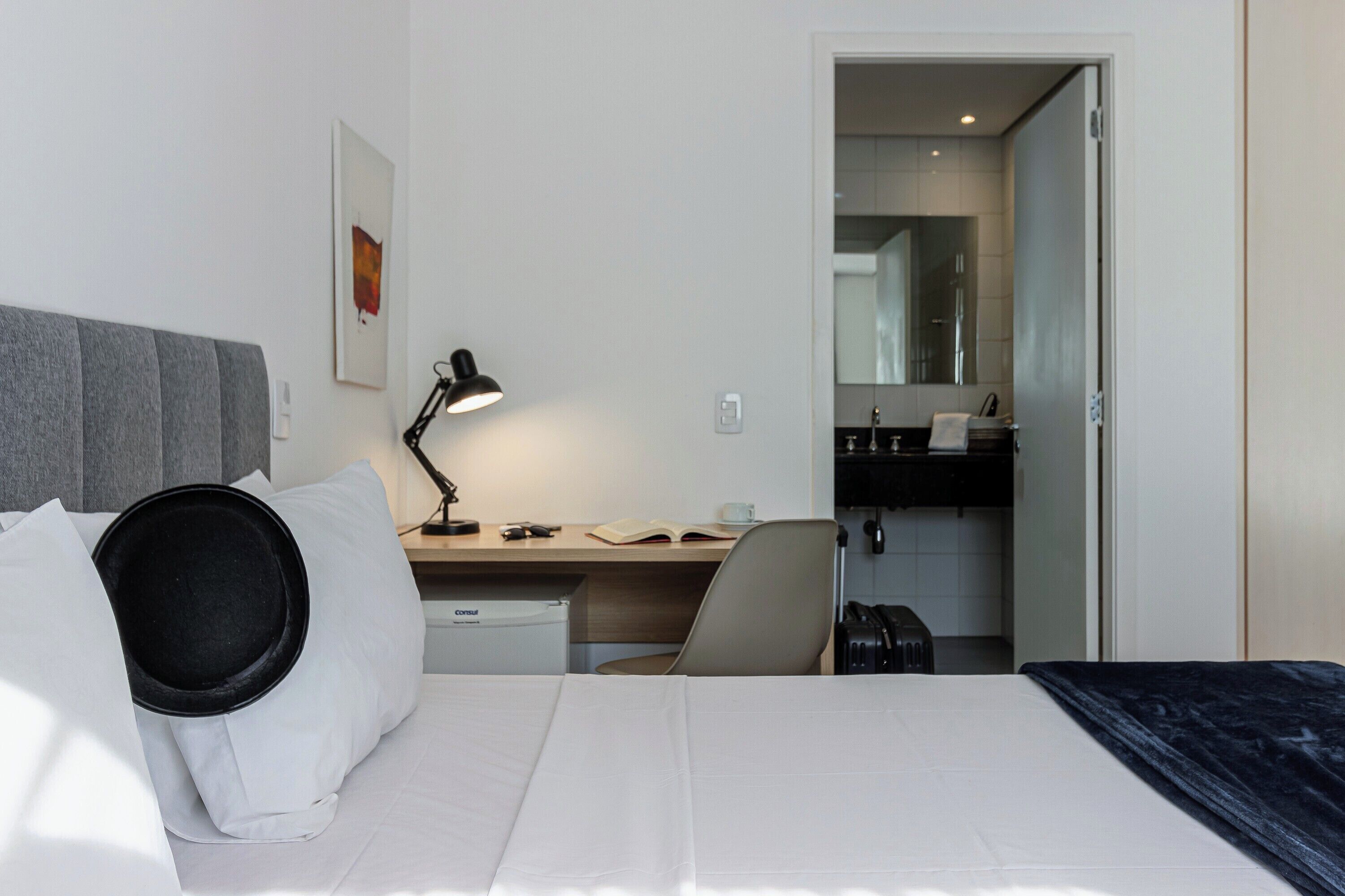 Et hotelværelse med seng, skrivebord, stol og et tekøkken.