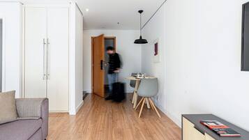 A modern living space with a sofa, a dining table with chairs, and a small cabinet with books.